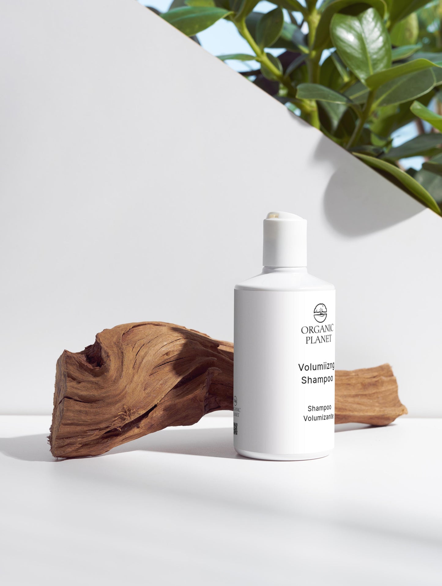 White bottle of shampoo with wooden piece and plant in background.