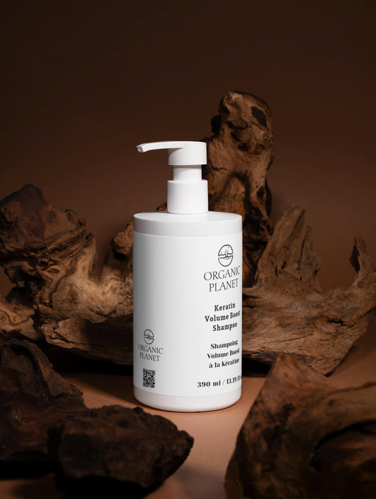 White bottle of Organic Planet shampoo on a brown background with natural elements. Keratin Volume Boost Shampoo